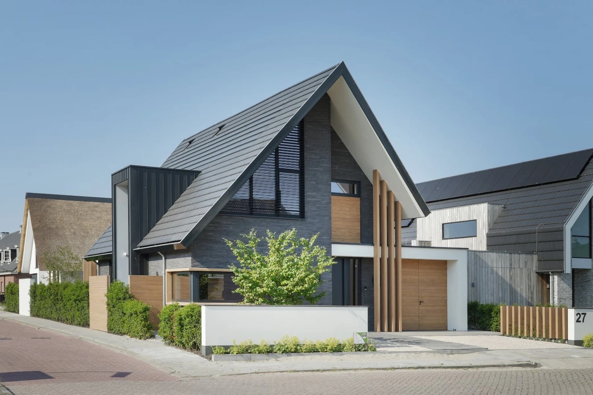 Voorkant woning met donkere gevel, houten accenten en metalen dak