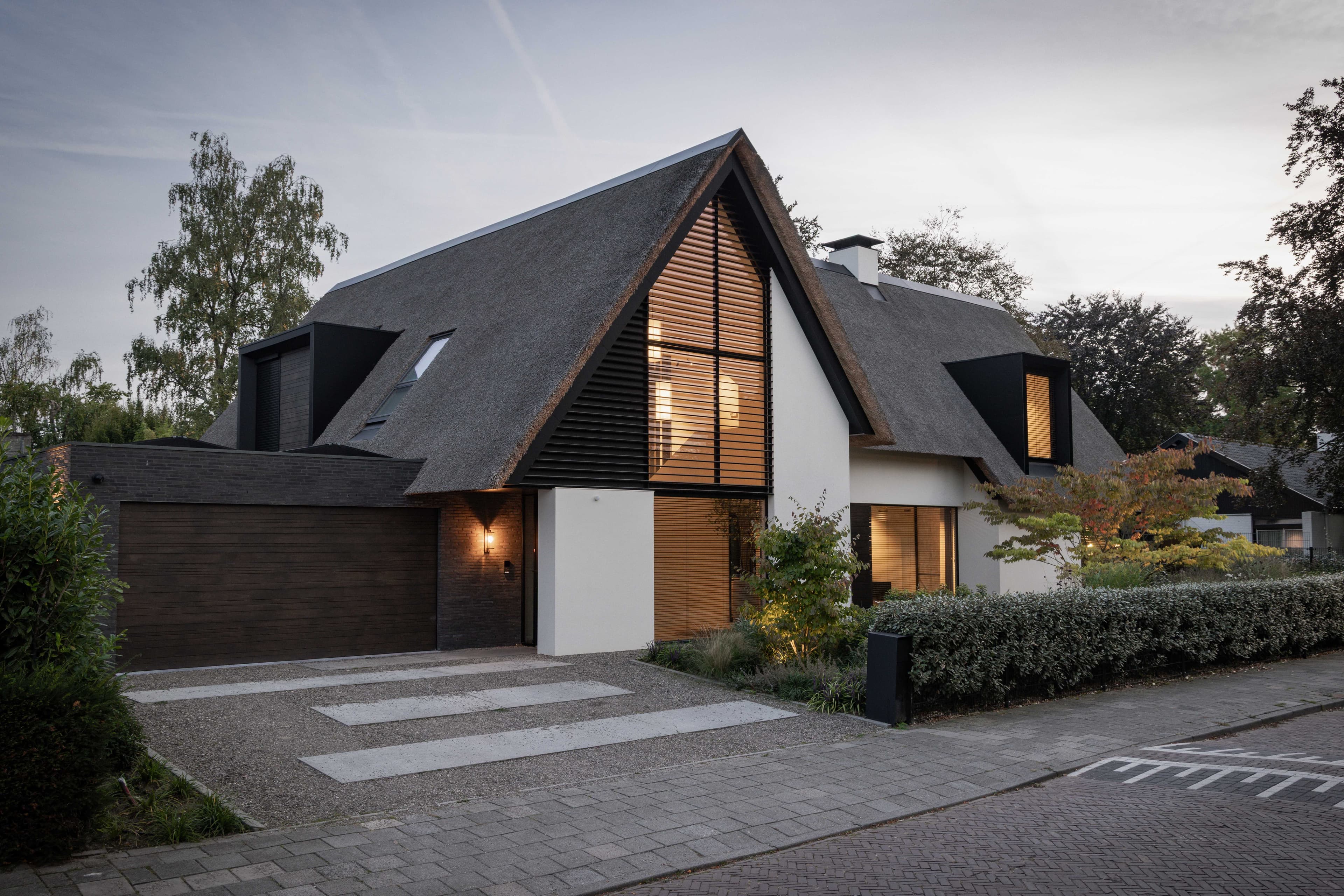 Zijgevel rietgedekte woning met zwarte en witte vlakken, houten raamomlijstingen