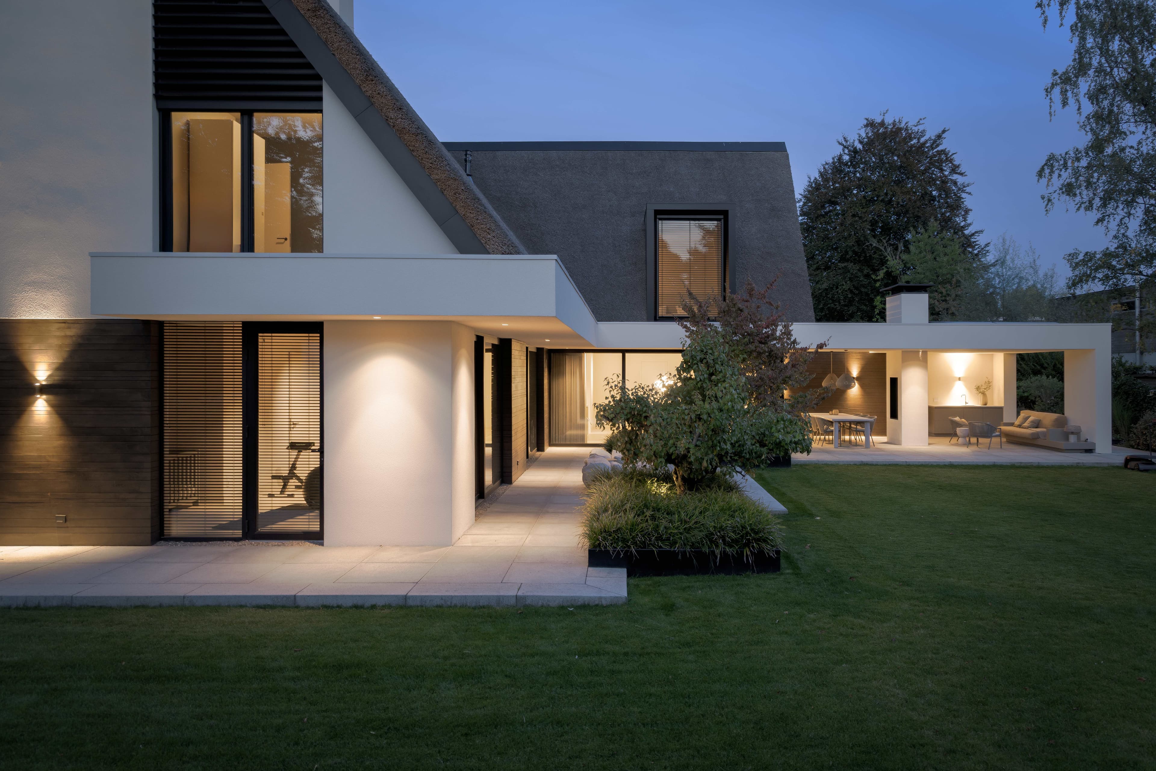 Moderne villa met rietgedekt dak, wit stucwerk en zwarte houten accenten