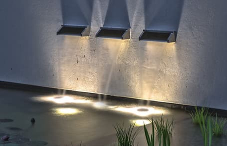 Houten dektuin met aangelicht waterkanaal en stenen paden