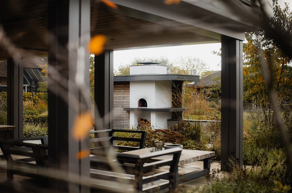 Overdekt terras met uitzicht op houten tuinhuisje en herfstvegetatie