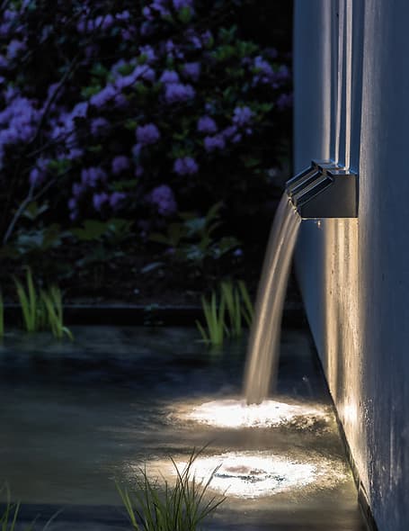 Watervallichtontwerp langs betonnen wand met natuurlijke planten