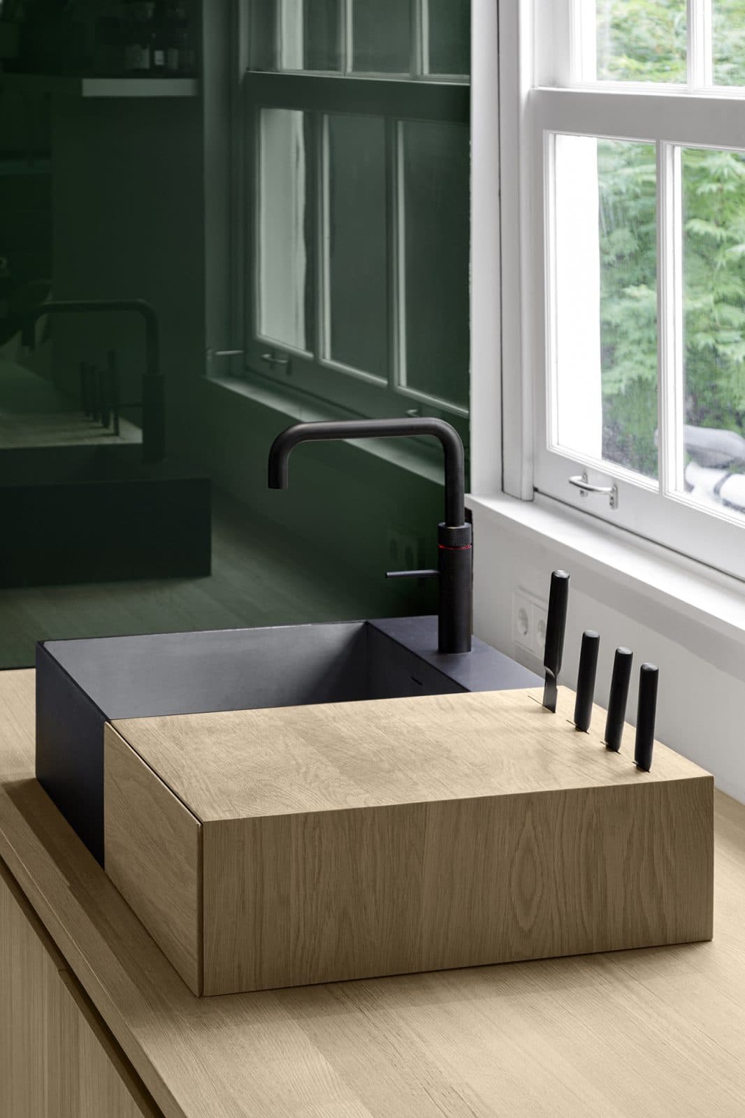Badkamer met zwarte wastafel, eikenhouten blad en grote groene spiegels