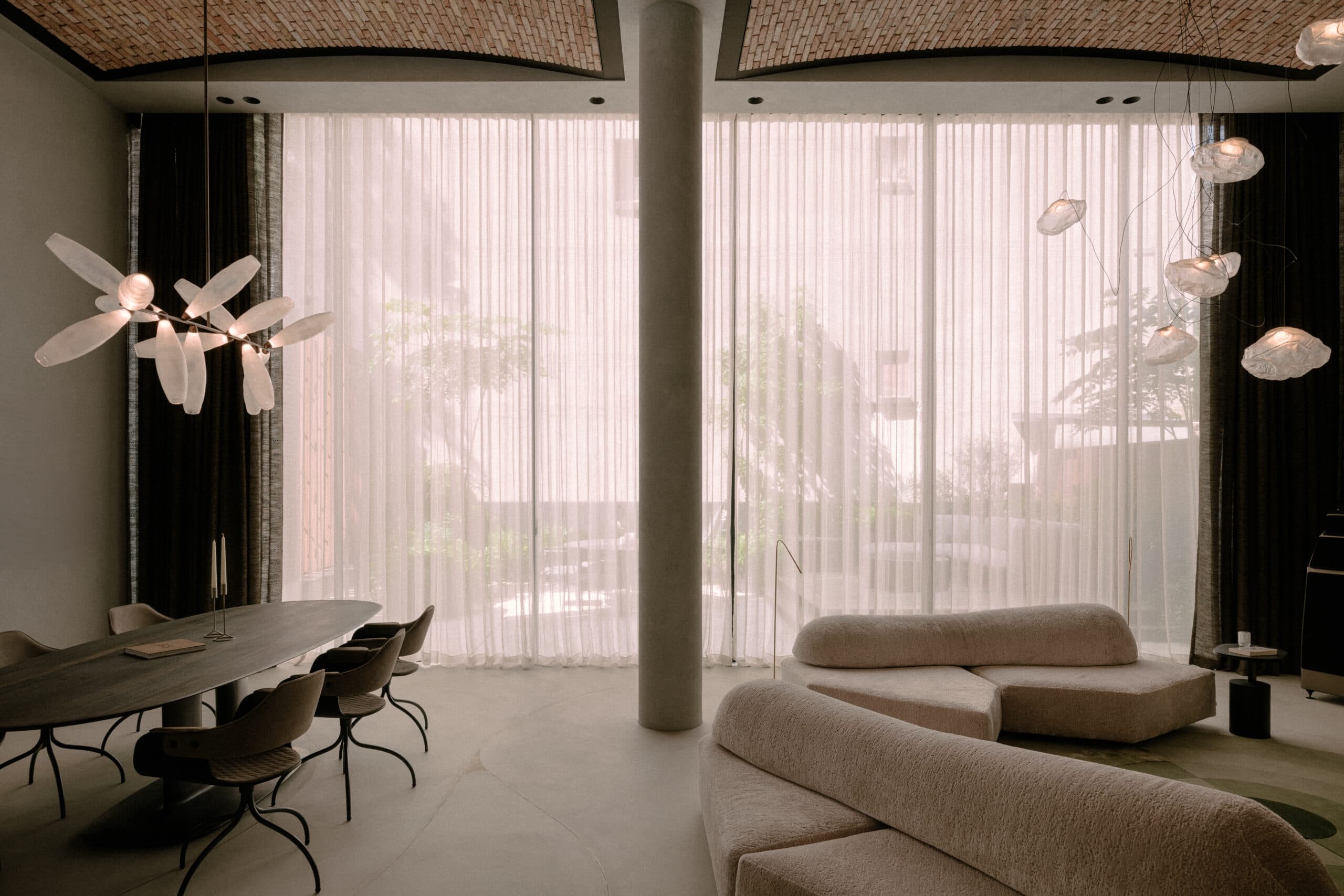 Woonkamer met verticale lamellen, grote ramen en beige zitmeubels