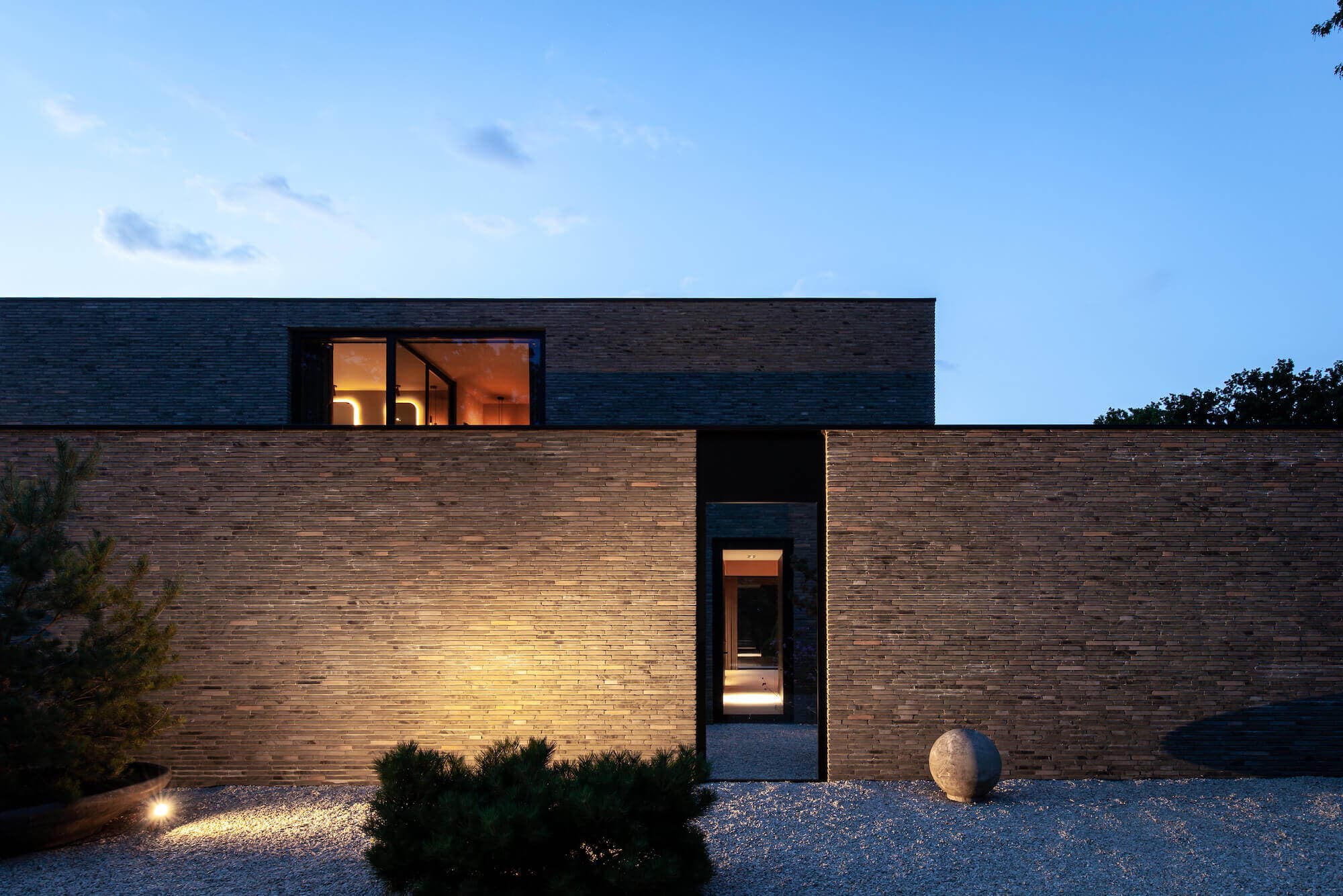 Voorgevel bakstenen villa met minimalistisch ontwerp en grindoppervlak