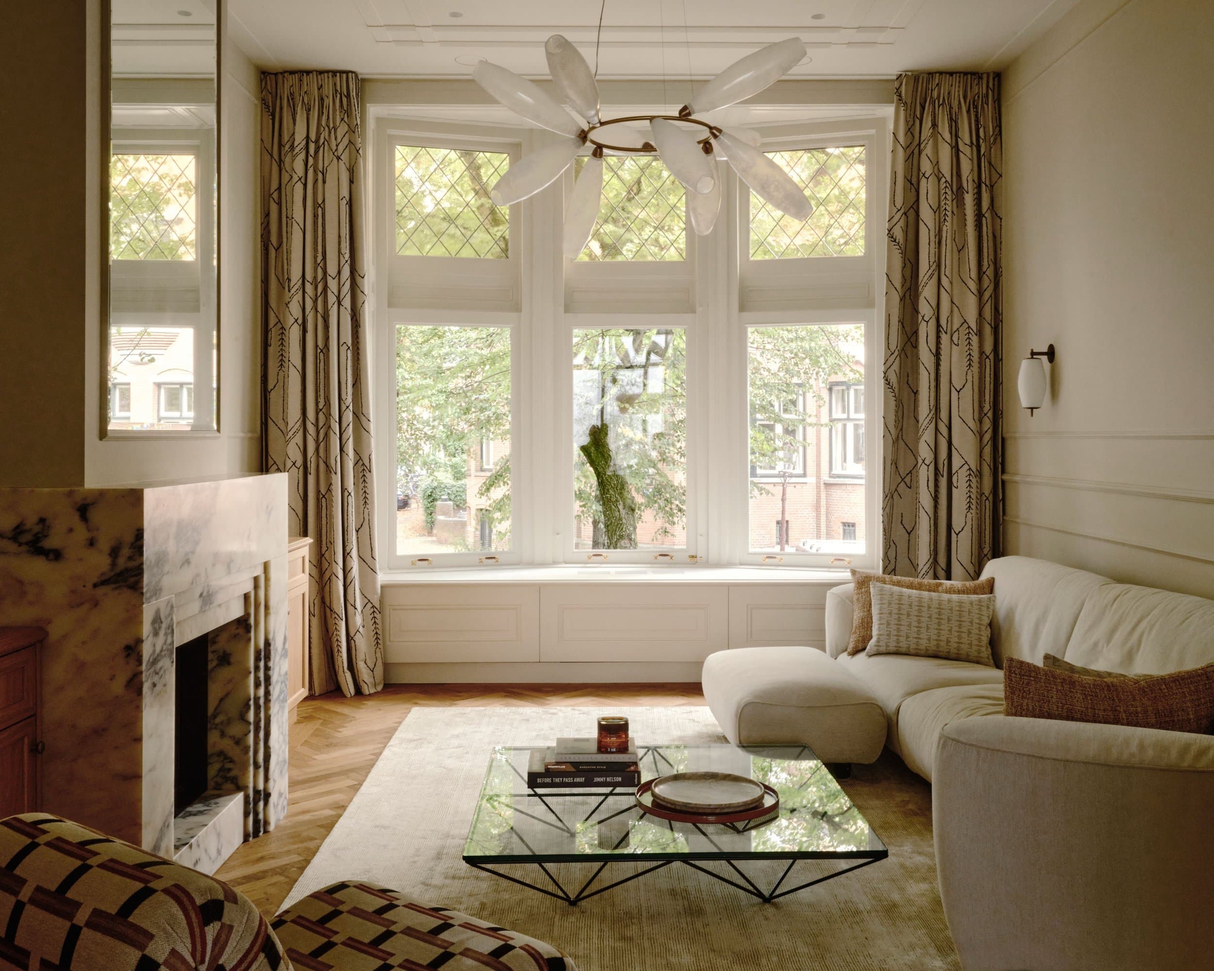 Elegant woonkamer met grote ramen, gemarmerde schouw en beige linnen zitmeubels