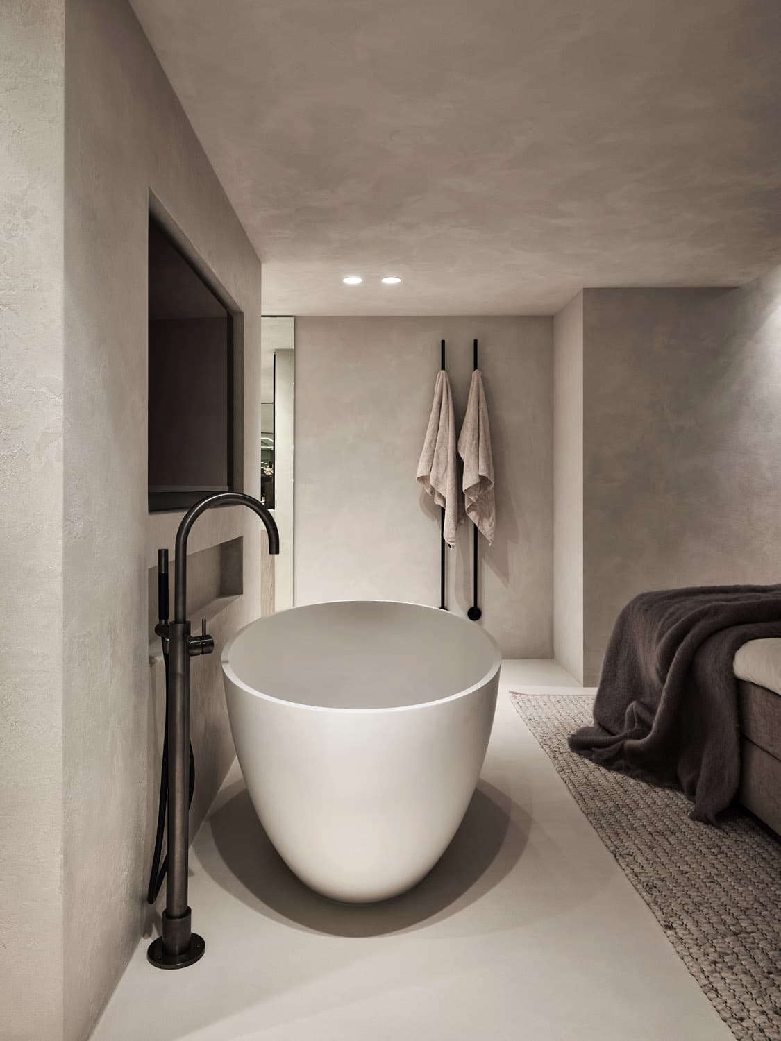 Minimalistische badkamer met vrijstaand wit bad en zwarte kraan