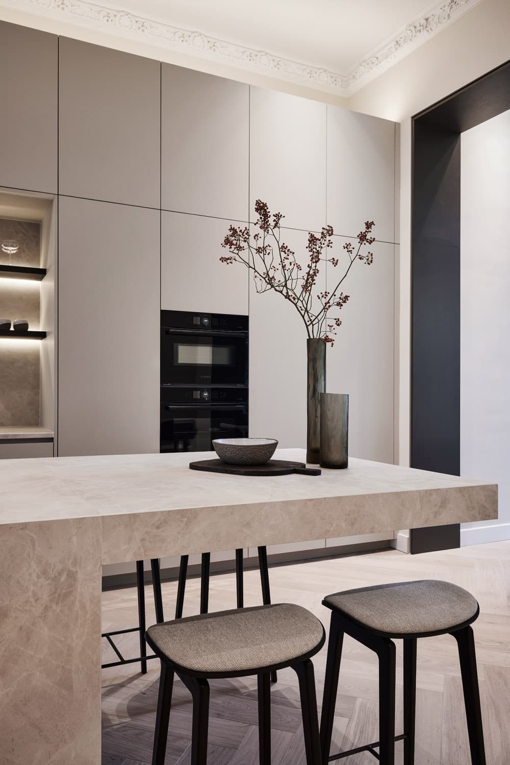 Minimalistische keuken met witte fronten, zwarte inbouwapparatuur en barkasten