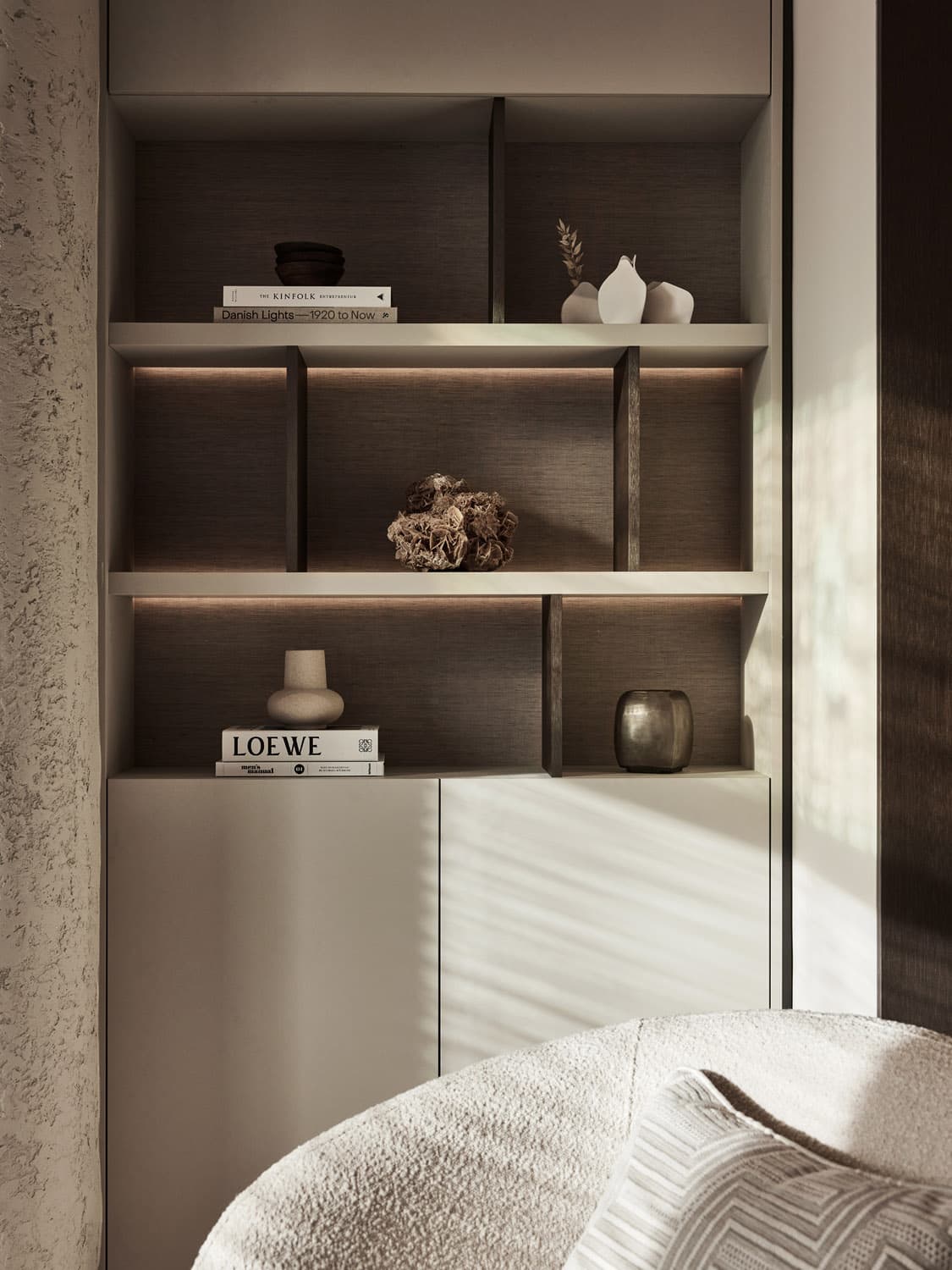 Inbouwkast met donkergestreepte achterwand en witte planken met decoratie