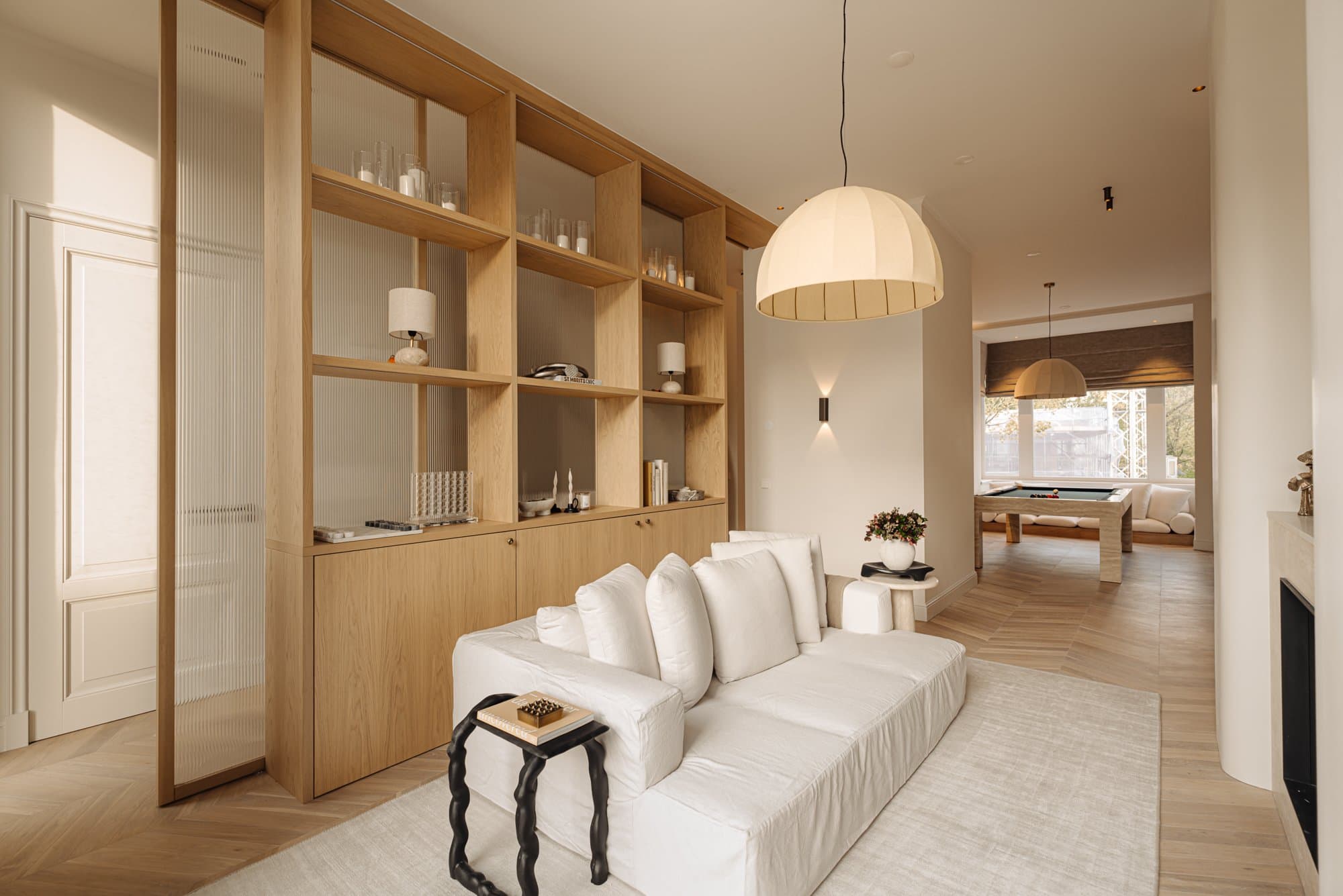 Openplan woonruimte met eikenhouten kastenwand en design hanglamp