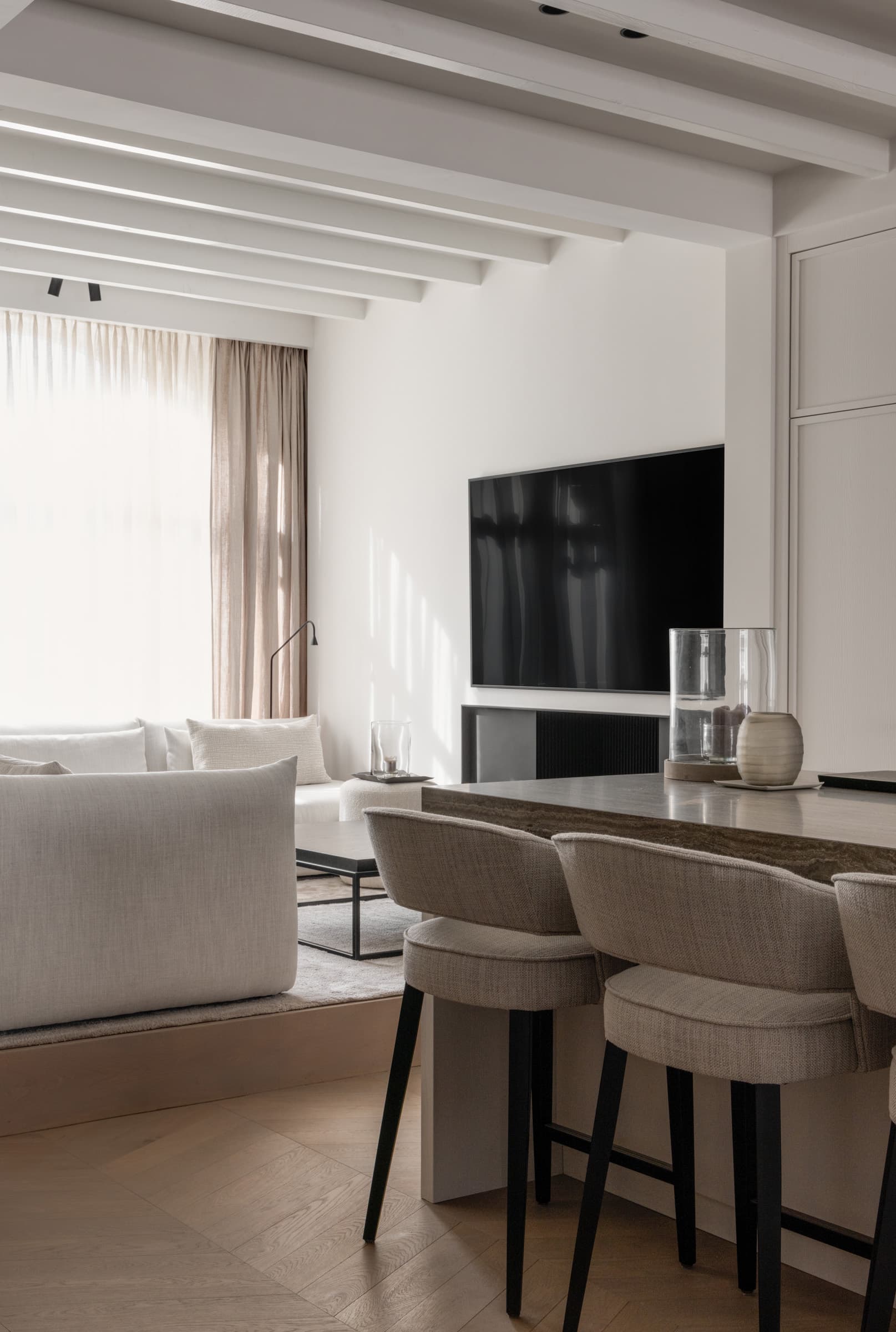 Woonkamer met beige stoelen, tv-meubel en balkenplafond
