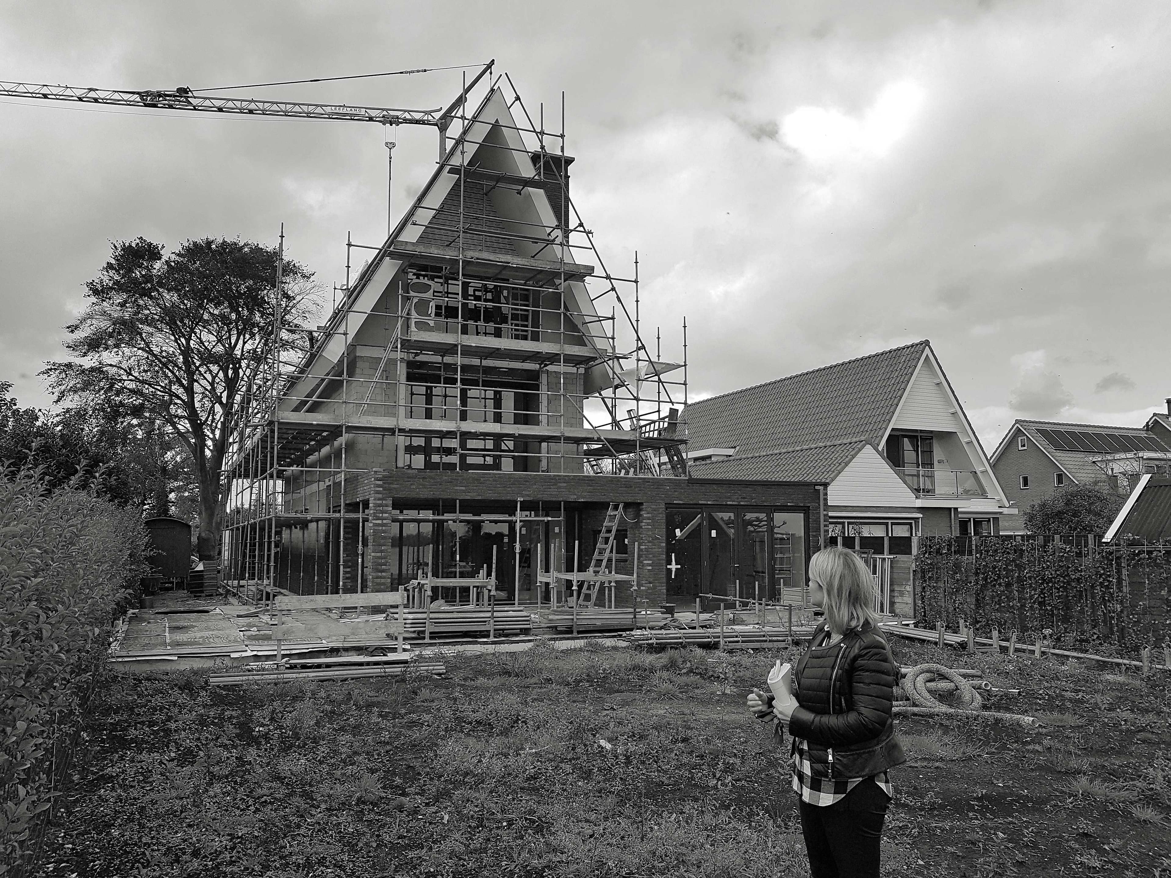 Villa in aanbouw met steigers, bakstenen fundering en moderne architectuur
