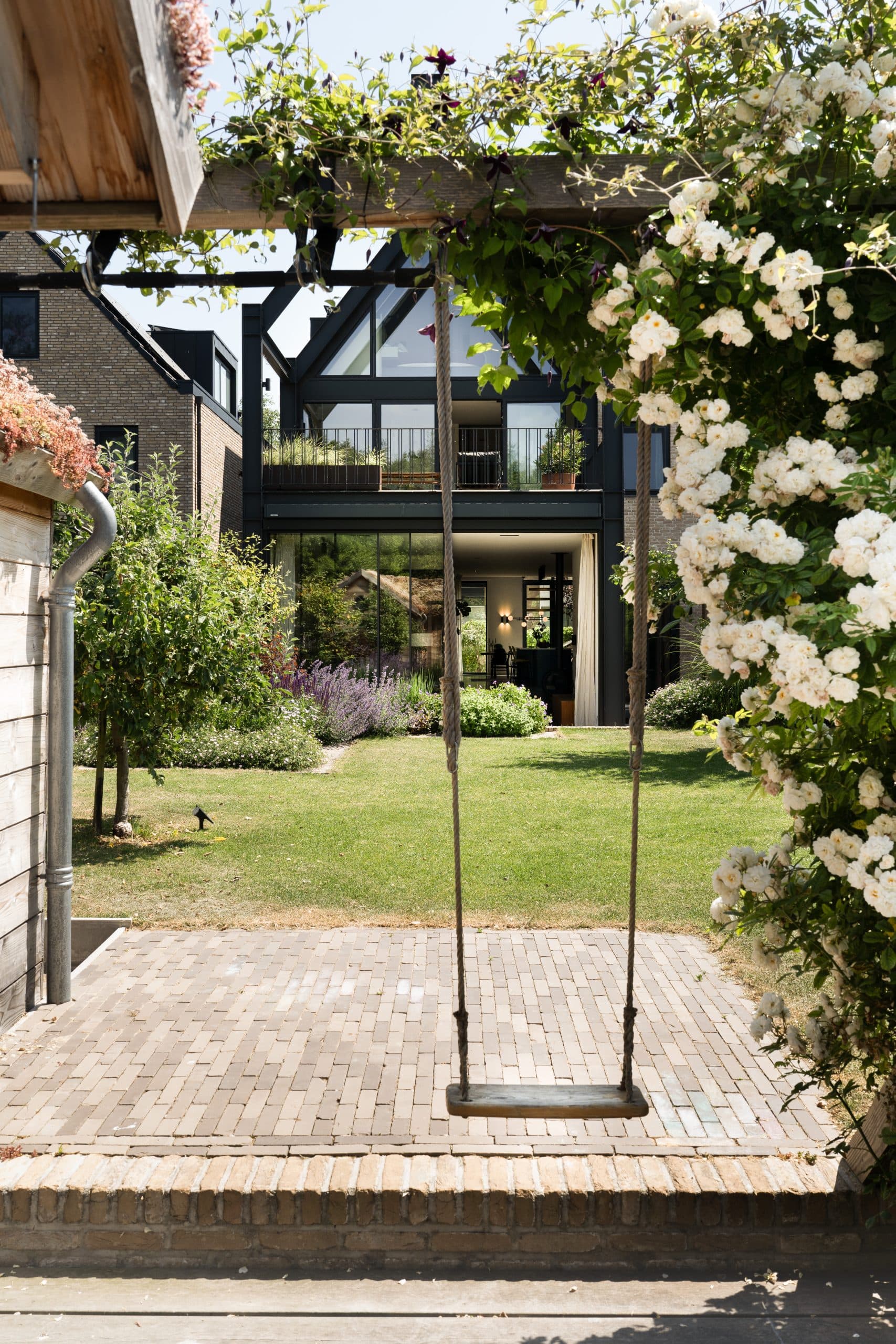 Moderne tuinkamer met zwart staal frame, grote schuifpuien, bloeiende borders