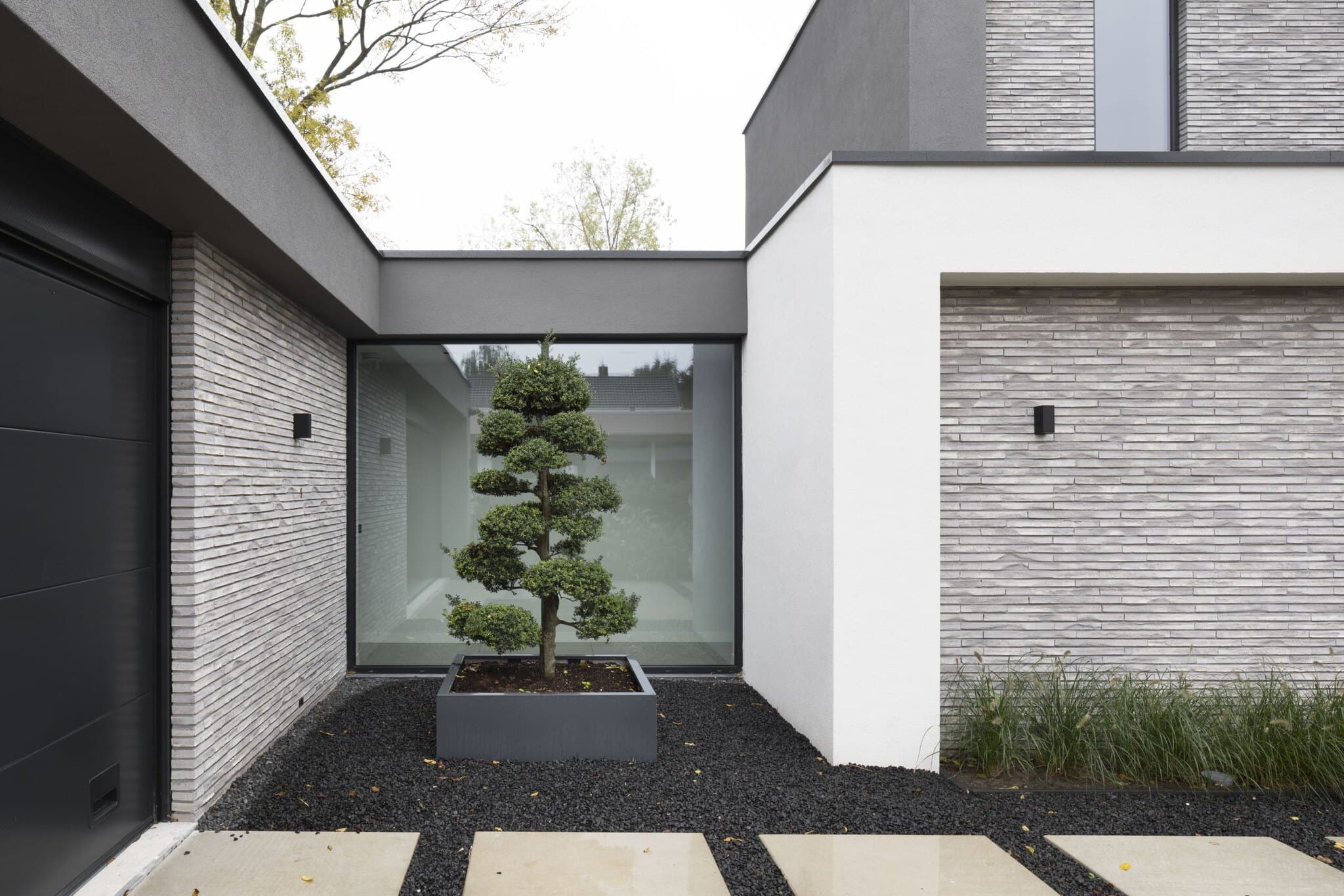 Moderne garage met binnenplaats, zwarte stenen en bonsai-boompje