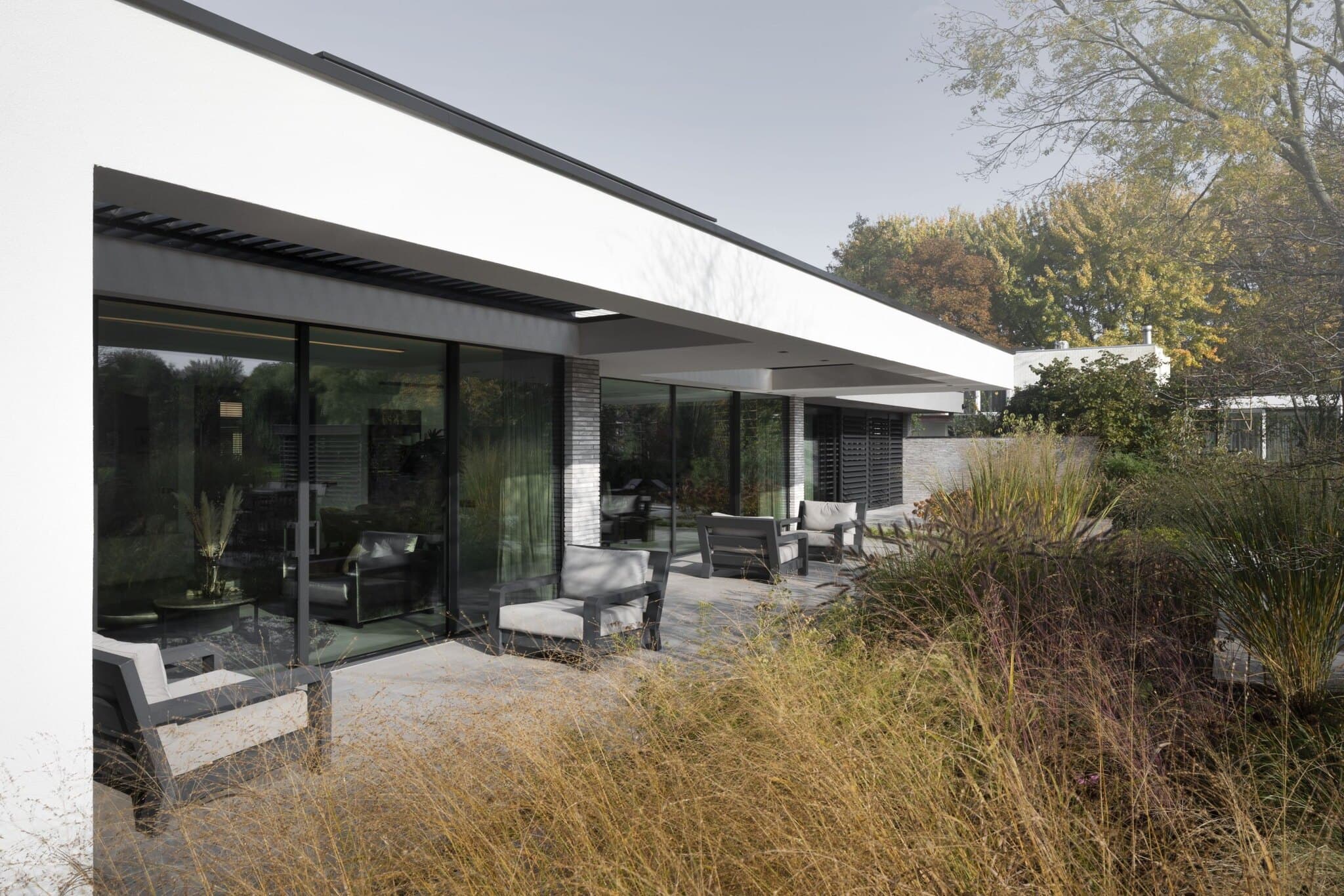 Gevelopbouw met grote glazen puien, betonnen terras en siergras