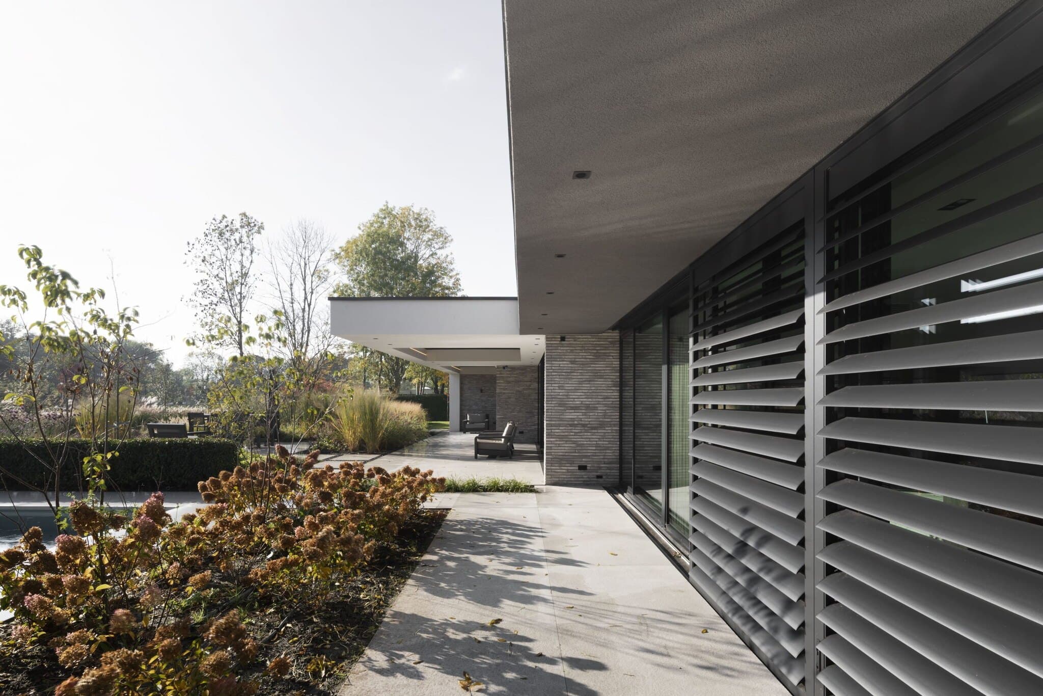 Moderne villa met donkergrijze lamellenschermen en terras