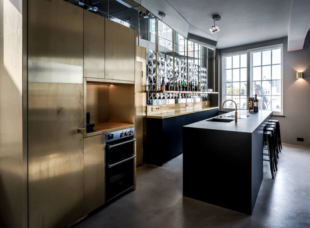 Keuken met goudkleurige kasten, zwart eiland en geslepen glasdeuren