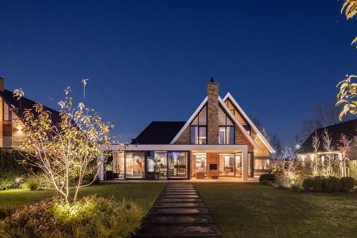 Moderne villa 's avonds verlicht met bakstenen voorgevel en stenen pad