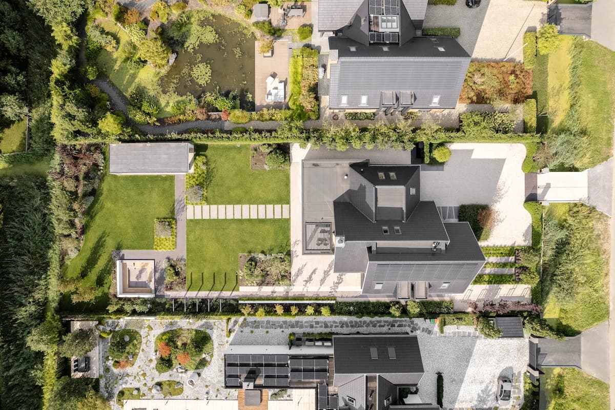Luchtfoto vrijstaande huizen met aangelegde tuinen en grijze oppervlakken