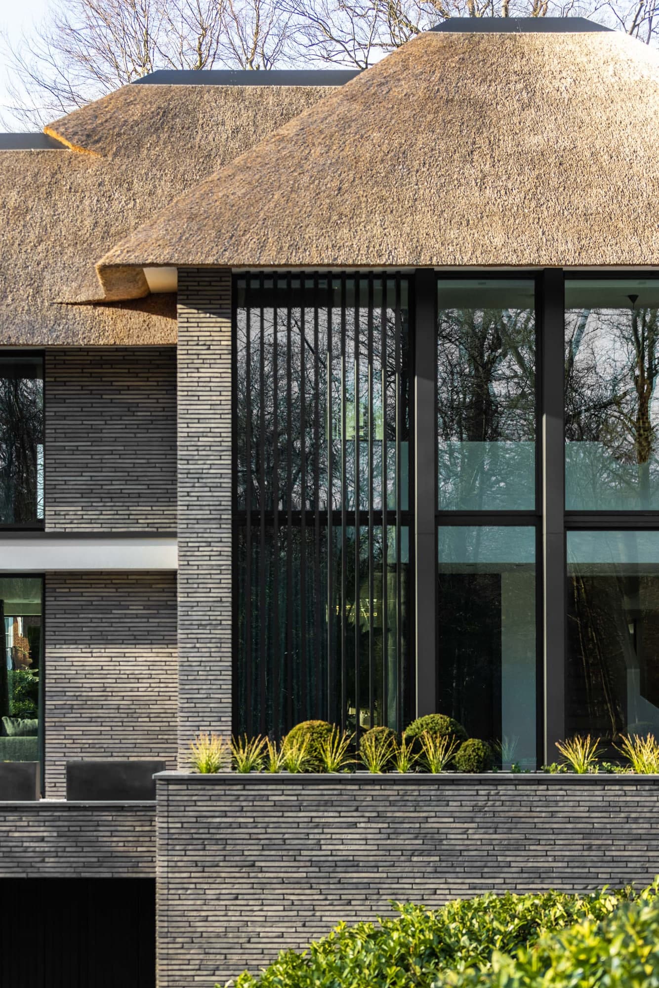 Villa voorgevel met donkere steen en verlichte tuin
