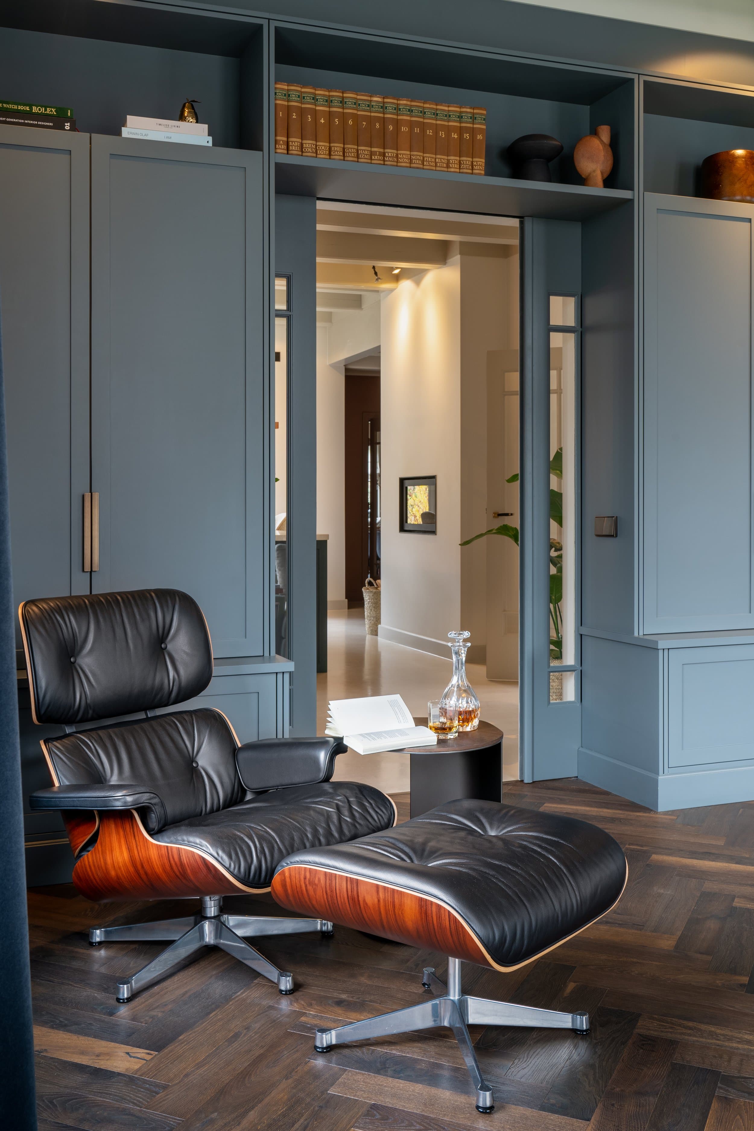 Lounge hoek met zwarte leren Eames-stoel en grijze inbouwkasten