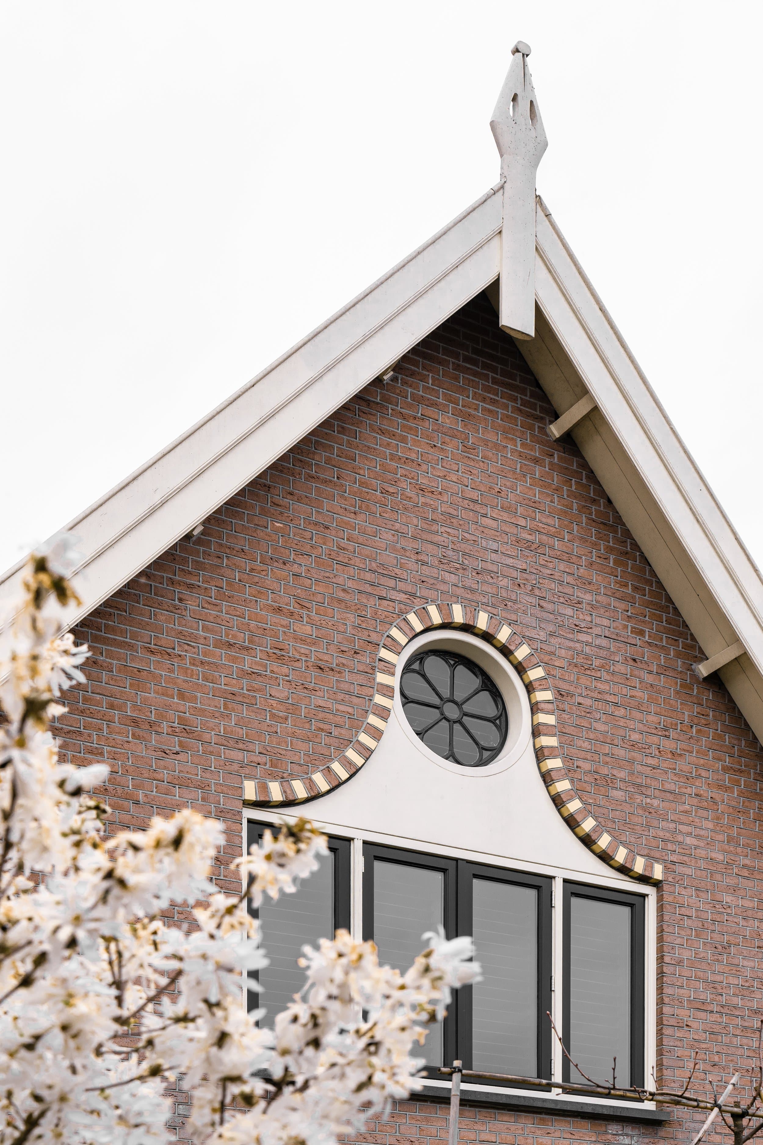 Baksteinen kerkgebouw met wit houten daklijsten en ronde raam