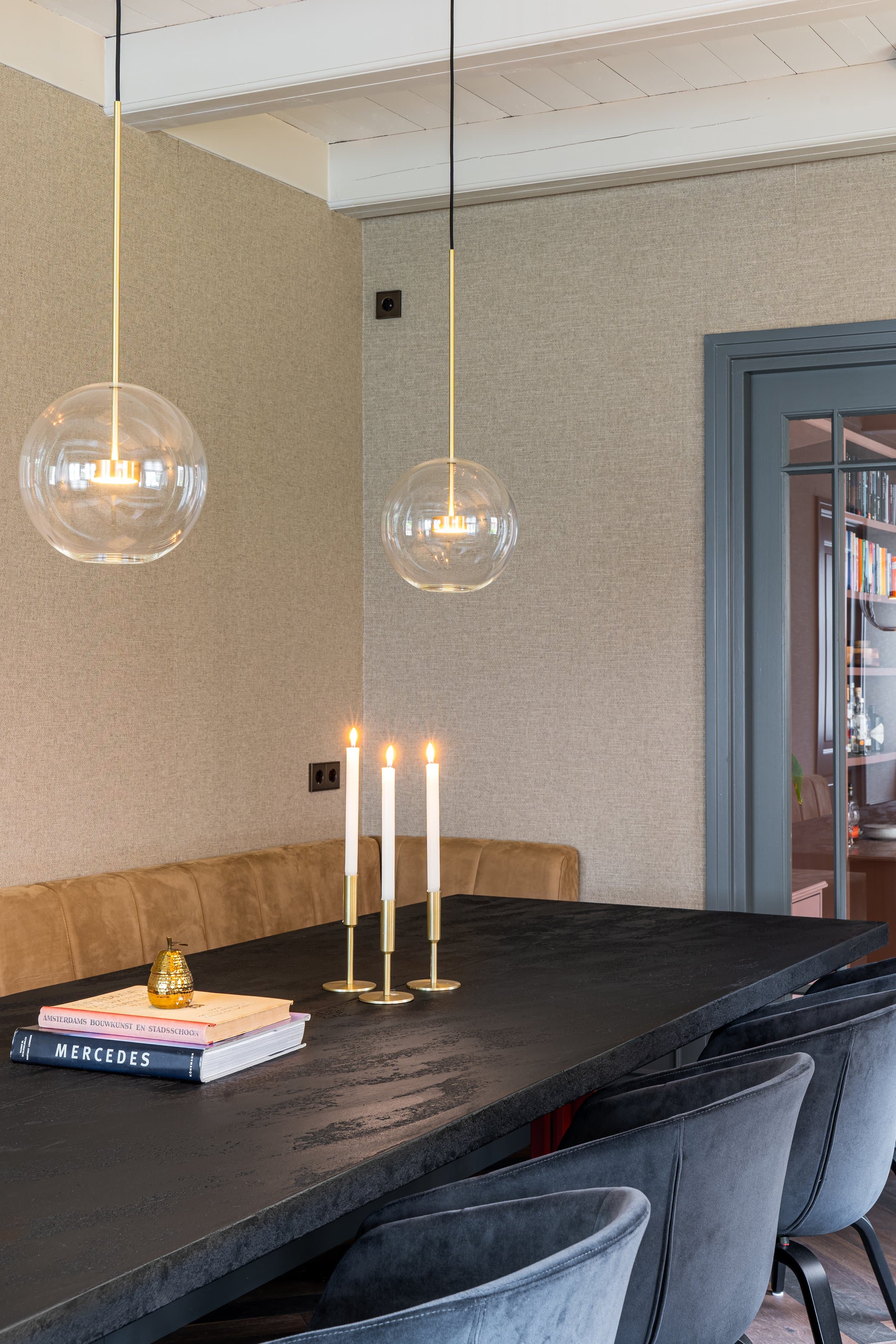 Eetkamer met donker werkblad, glazen hanglamp en beige zijwand