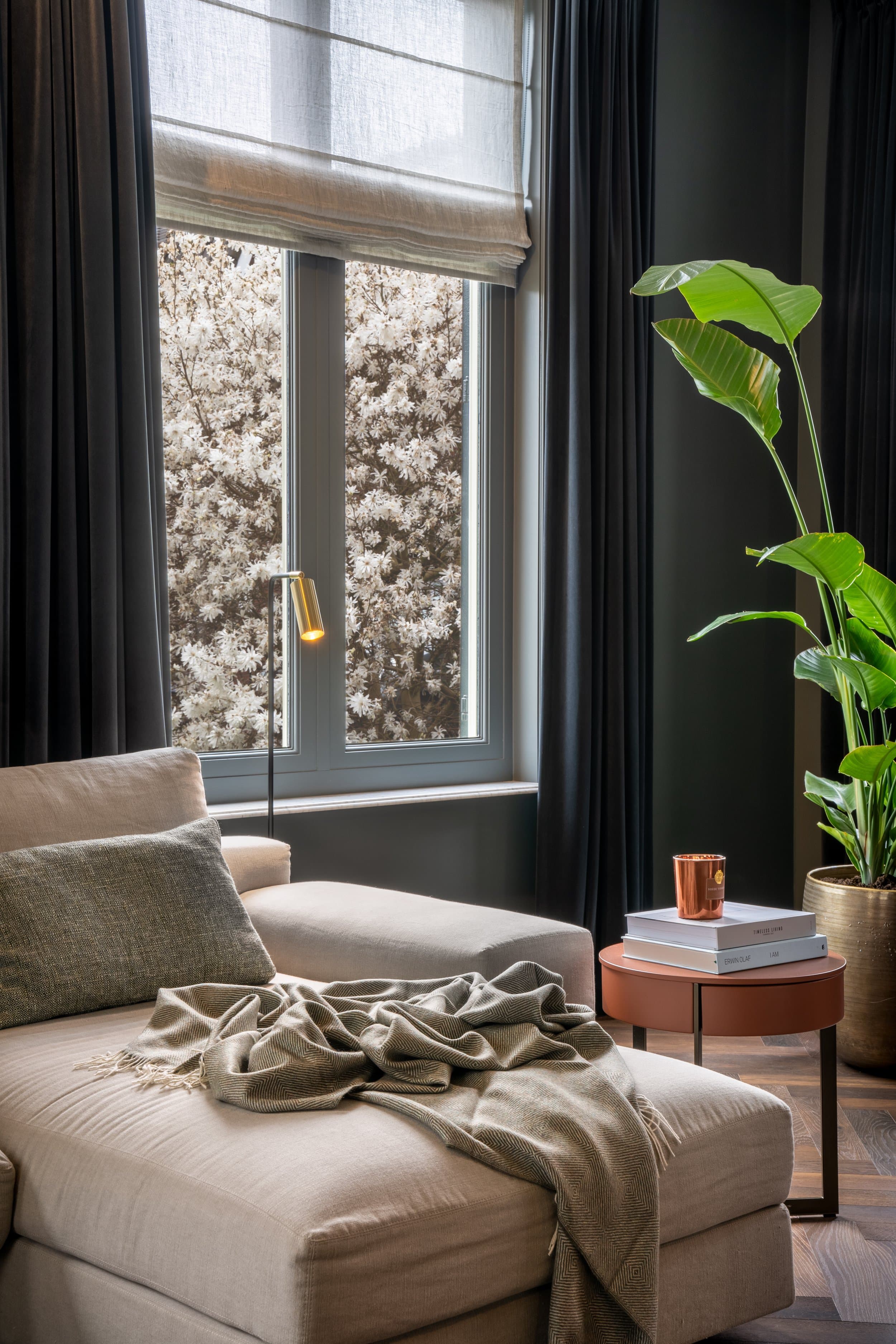 Zithoek met beige fauteuil, grijze gordijnen en grote raampartij