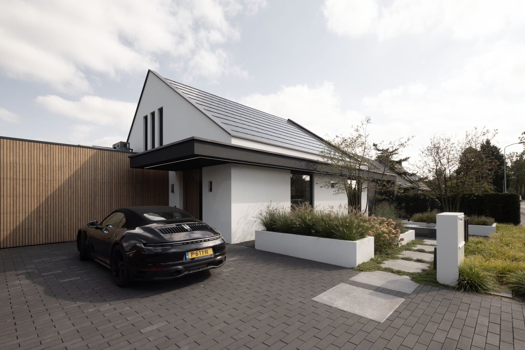 Moderne villa met cortenstaal schuur en zwarte elektrische auto