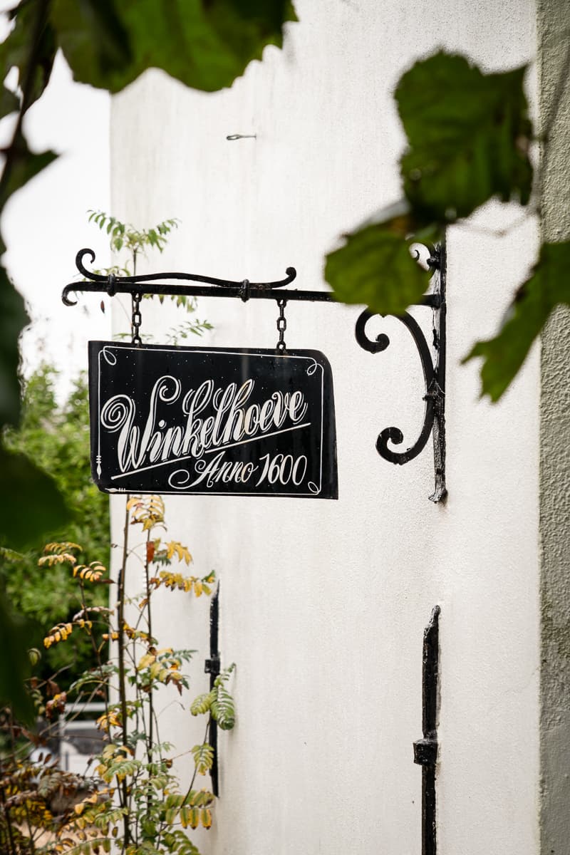 Witte gevel met zwarte decoratief smeedijzeren uithangbord anno 1600