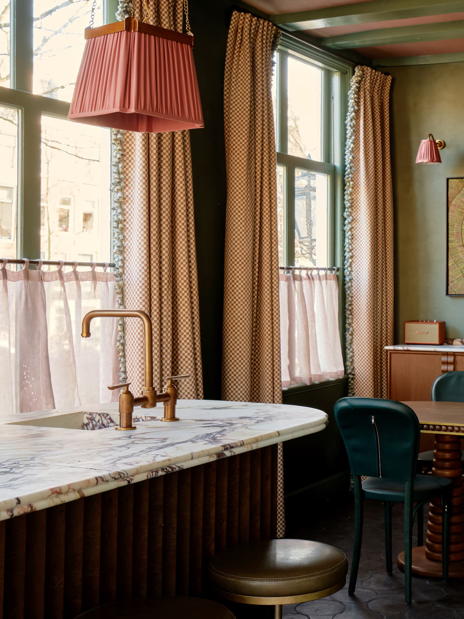 Badkamer met marmeren wastafel, roze hanglamp en goudkleurige kraan
