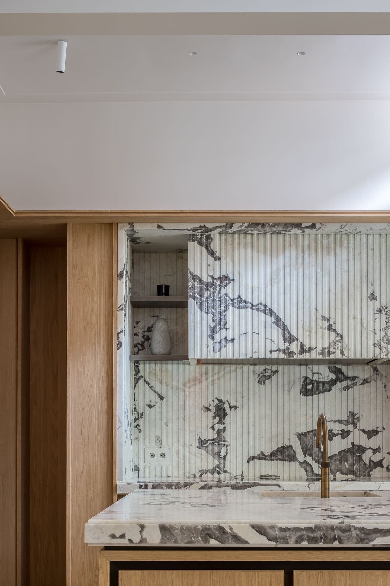 Keuken detail met marmeren werkblad, roestvrijstalen apparatuur en eikenhouten kastenwand