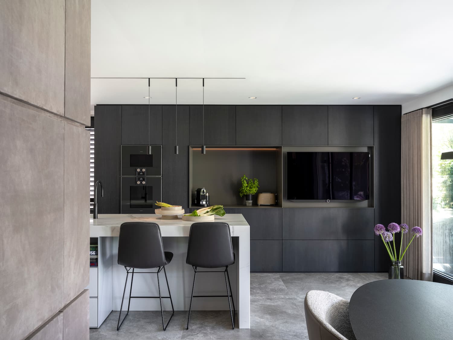 Moderne keuken met zwarte kasten, marmeren eiland en hangende verlichting