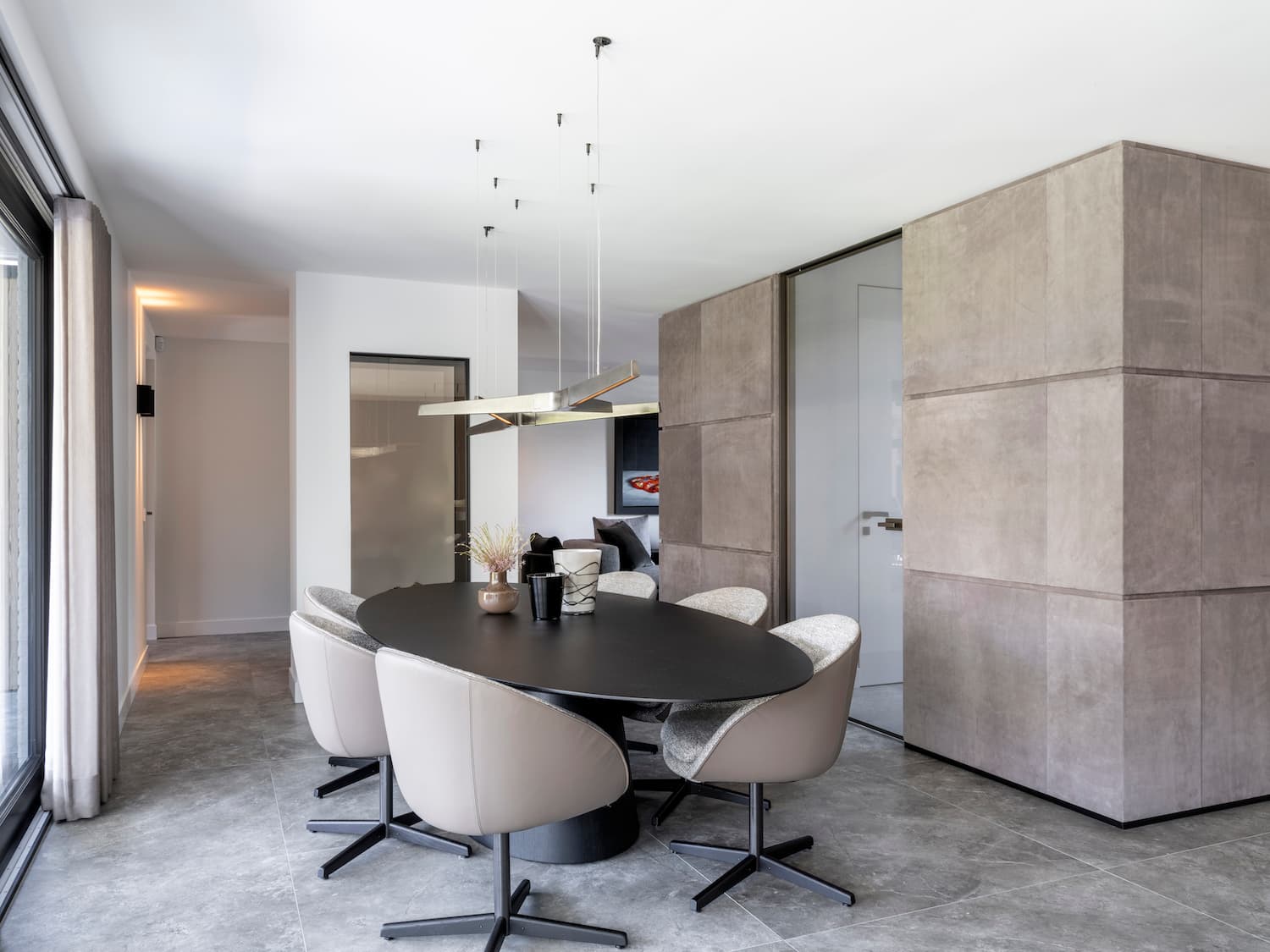 Ronde eettafel met design stoelen onder zwevend betonplafond